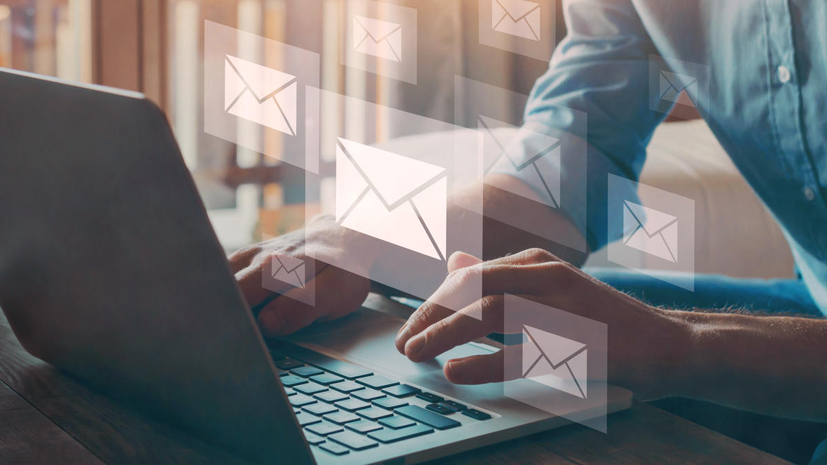 Hands on laptop with floating email icons, showing how dmarc for small business helps stop email spoofing.
