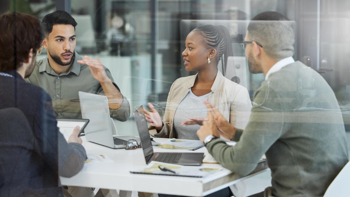 Small business team discussing cloud migration steps, risks, and data backup at a conference table with laptops.
